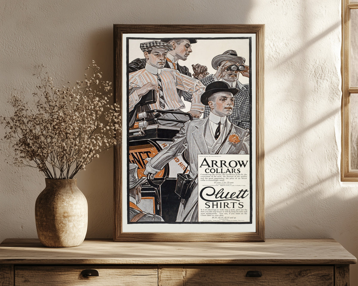 Framed art print of Arrow Collars & Cluett Shirts by J.C. Leyendecker, in a dark wood frame leaning on a rustic console beside dried flowers