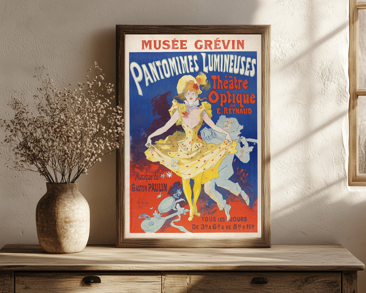 Framed art print of Pantomimes lumineuses by Jules Chéret, in a dark wood frame leaning on a rustic console beside dried flowers