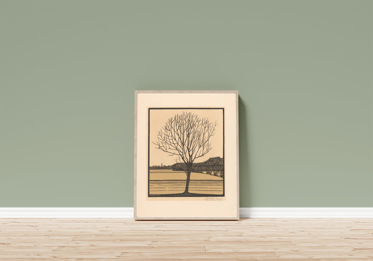 Framed art print of Bare Tree in Field by Julie de Graag, in a light wood frame leaning on a sage green wall above a wooden floor