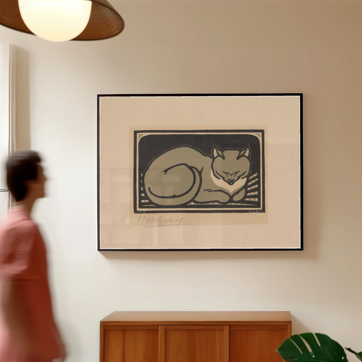 Framed art print of Sleeping Cat by Julie de Graag, in a slim black frame on a warm wall in a sunlit room