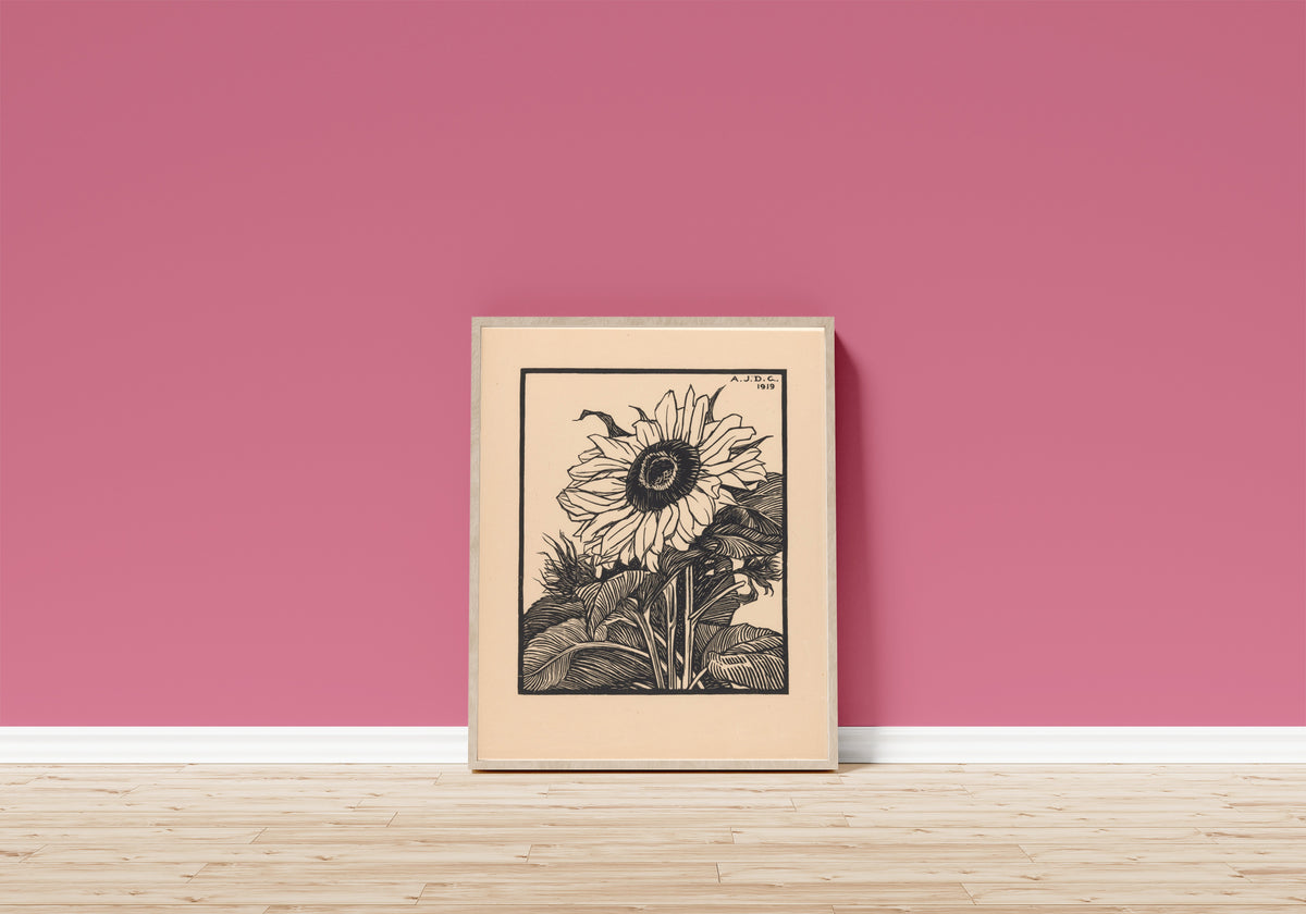 Framed art print of Sunflower by Julie de Graag, in a light wood frame leaning on a pink wall above a wooden floor