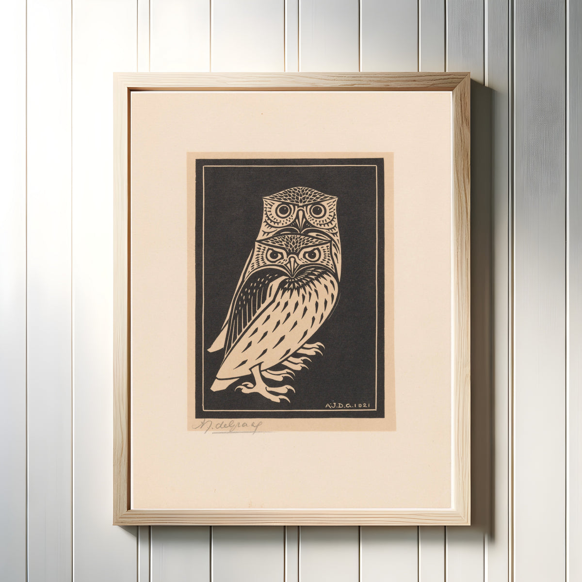Framed art print of Two Owls by Julie de Graag, in a light wood frame on a white panelled wall