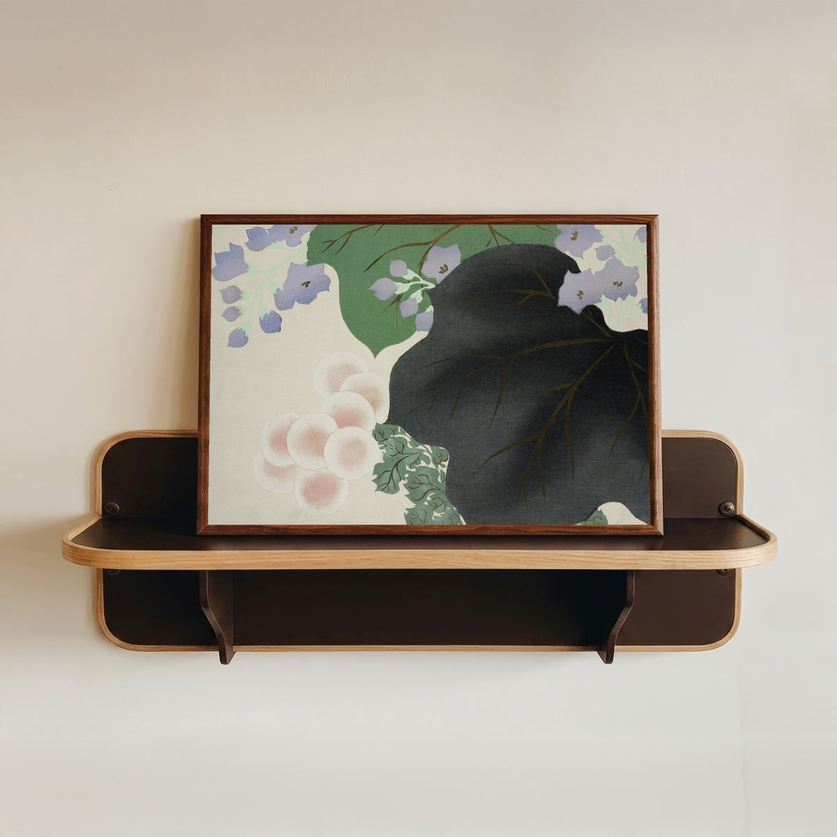 Framed art print of Flowers and leaves, from Momoyogusa by Kamisaka Sekka, in a dark wood frame resting on a wall shelf