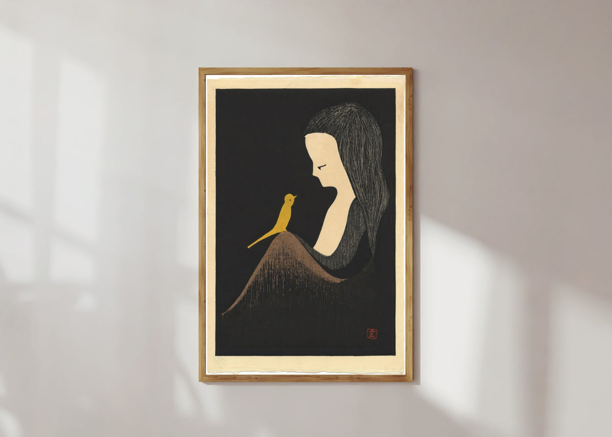 Framed art print of Girl with Yellow Bird by Kaoru Kawano, in a light wood frame on a sunlit white wall