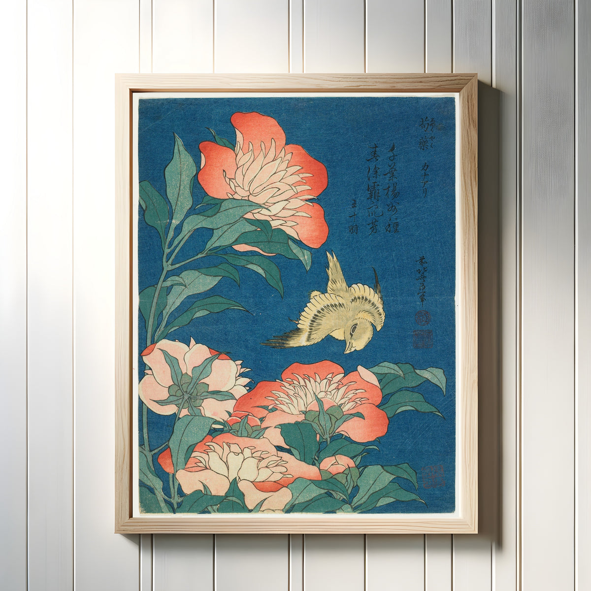 Framed art print of Peonies and Canary by Katsushika Hokusai, in a light wood frame on a white panelled wall