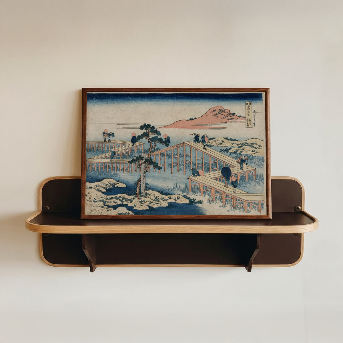 Framed art print of Remarkable Views of Bridges in Various Provinces: An Ancient Picture… by Katsushika Hokusai, in a dark wood frame resting on a wall shelf