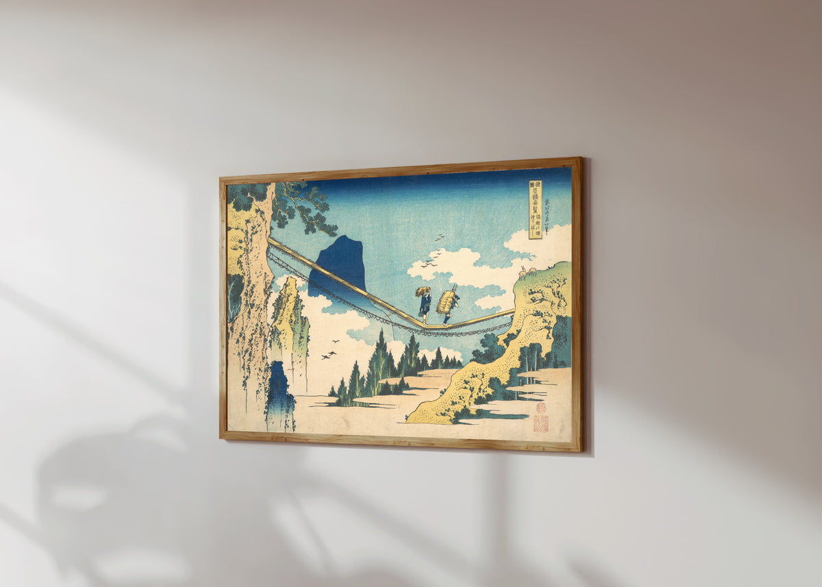 Framed art print of Remarkable Views of Bridges in Various… by Katsushika Hokusai, in a light wood frame on a sunlit white wall, seen at a slight angle