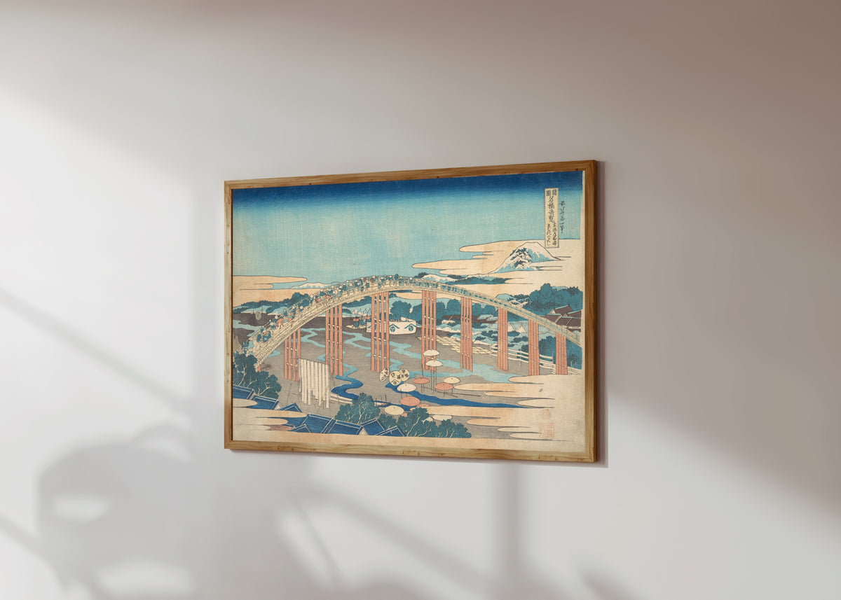 Framed art print of Remarkable Views of Bridges in Various… by Katsushika Hokusai, in a light wood frame on a sunlit white wall, seen at a slight angle