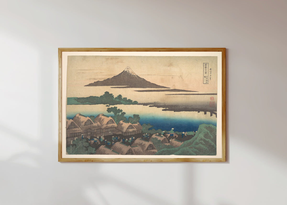 Framed art print of Thirty-six Views of Mount Fuji: Dawn at Isawa in Kai Province by Katsushika Hokusai, in a light wood frame on a sunlit white wall
