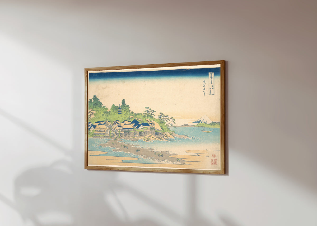 Framed art print of Thirty-six Views of Mount Fuji: Enoshima… by Katsushika Hokusai, in a light wood frame on a sunlit white wall, seen at a slight angle