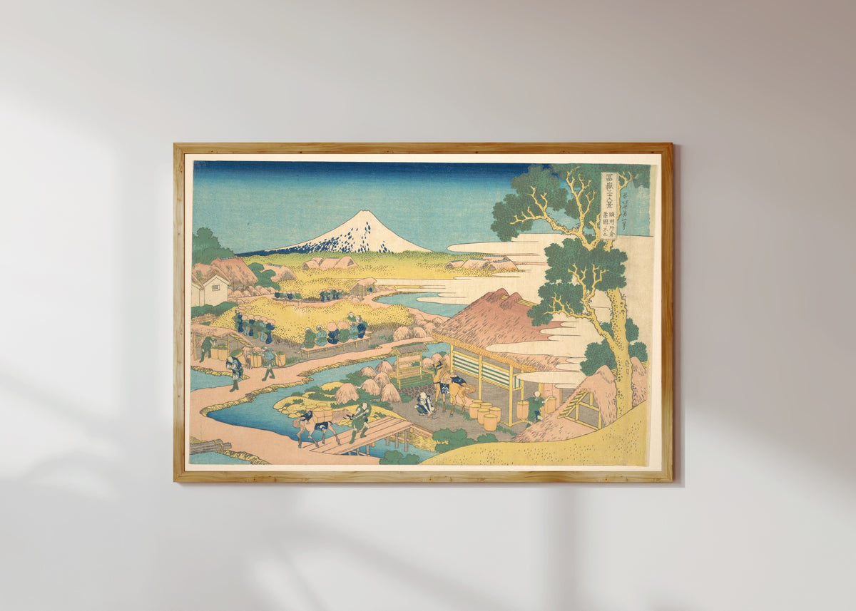 Framed art print of Thirty-six Views of Mount Fuji: Fuji from the Katakura Tea Fields in… by Katsushika Hokusai, in a light wood frame on a sunlit white wall