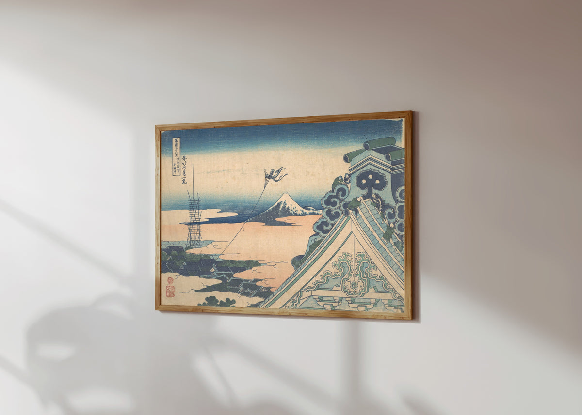 Framed art print of Thirty-six Views of Mount Fuji: Honganji at… by Katsushika Hokusai, in a light wood frame on a sunlit white wall, seen at a slight angle