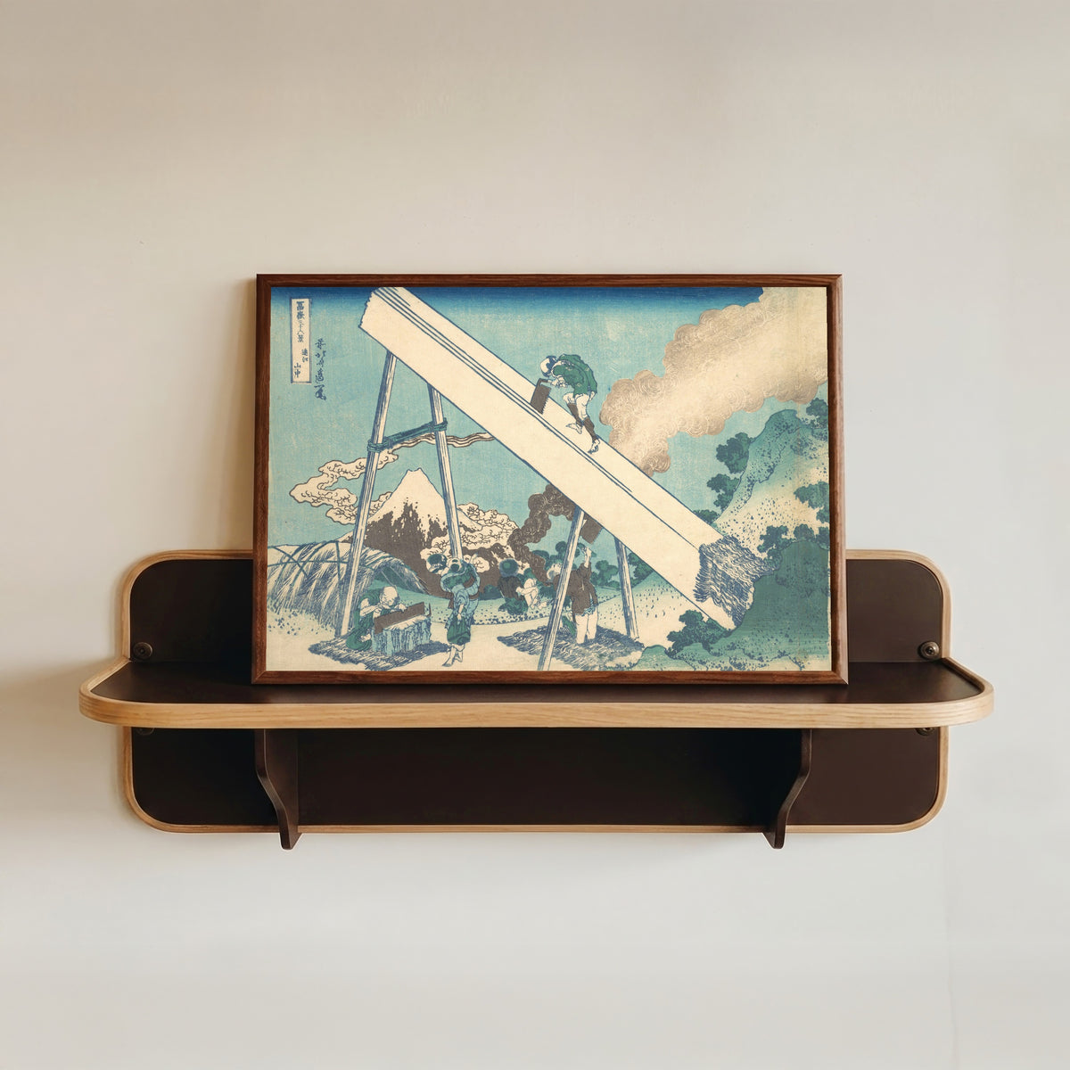 Framed art print of Thirty-six Views of Mount Fuji: In the Mountains of Tōtomi Province by Katsushika Hokusai, in a dark wood frame resting on a wall shelf