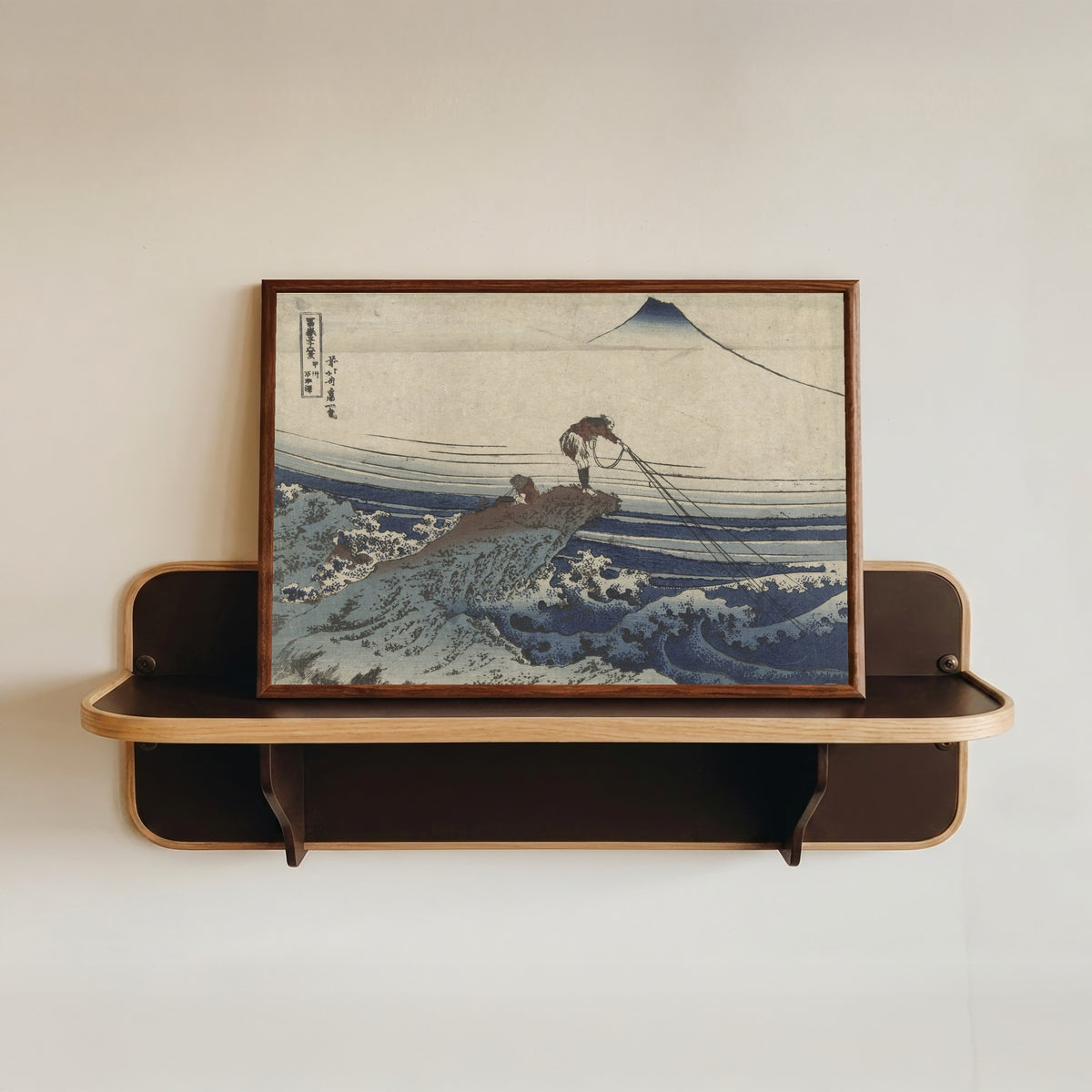 Framed art print of Thirty-six Views of Mount Fuji: Kajikazawa in Kai Province by Katsushika Hokusai, in a dark wood frame resting on a wall shelf