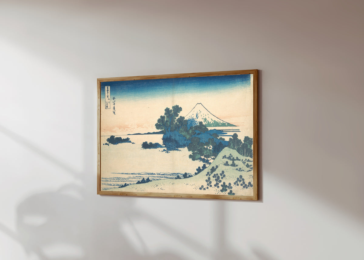 Framed art print of Thirty-six Views of Mount Fuji: Shichirigahama… by Katsushika Hokusai, in a light wood frame on a sunlit white wall, seen at a slight angle