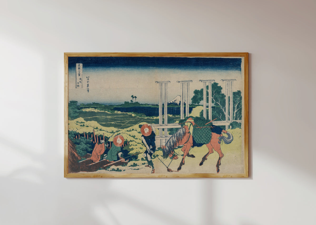 Framed art print of Thirty-six Views of Mount Fuji: The Weir at Senju in Musashi Province by Katsushika Hokusai, in a light wood frame on a sunlit white wall