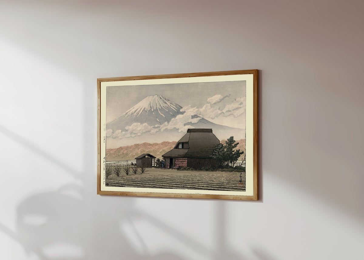 Framed art print of Countryside at Narusawa by Kawase Hasui, in a light wood frame on a sunlit white wall, seen at a slight angle