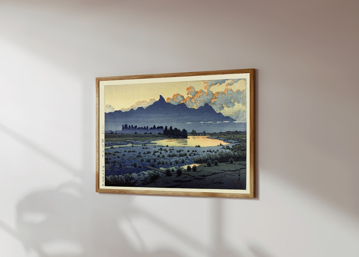 Framed art print of Maebashi Marshes by Kawase Hasui, in a light wood frame on a sunlit white wall, seen at a slight angle