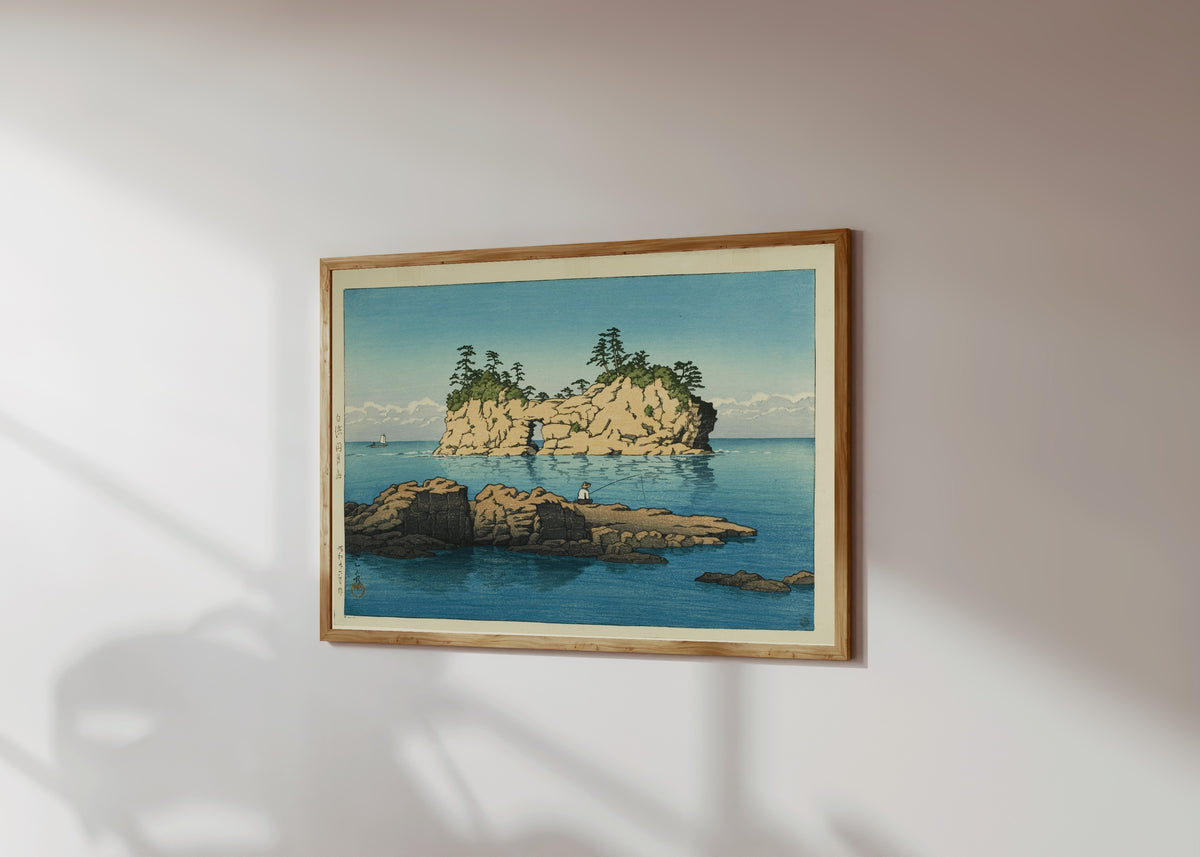 Framed art print of Engetsu Island, Shirahama by Kawase Hasui, in a light wood frame on a sunlit white wall, seen at a slight angle