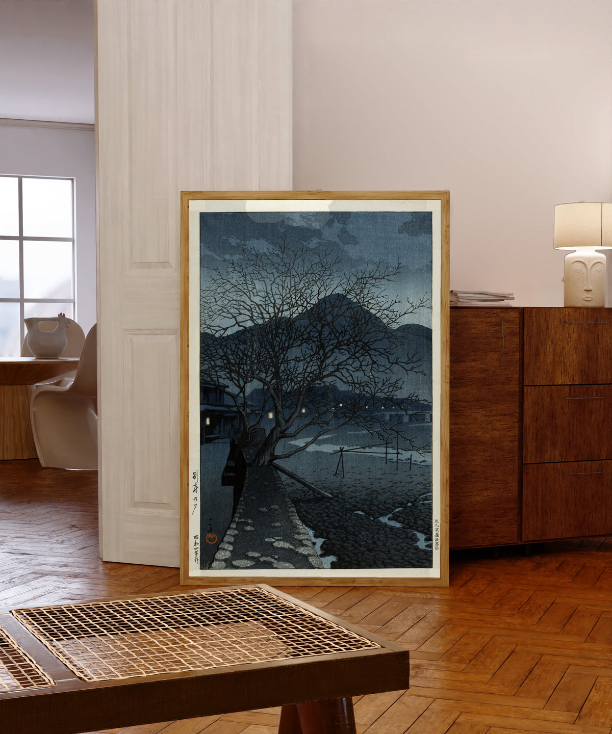 Framed art print of Evening in Beppu by Kawase Hasui, in a light wood frame leaning in a warm room with a parquet floor