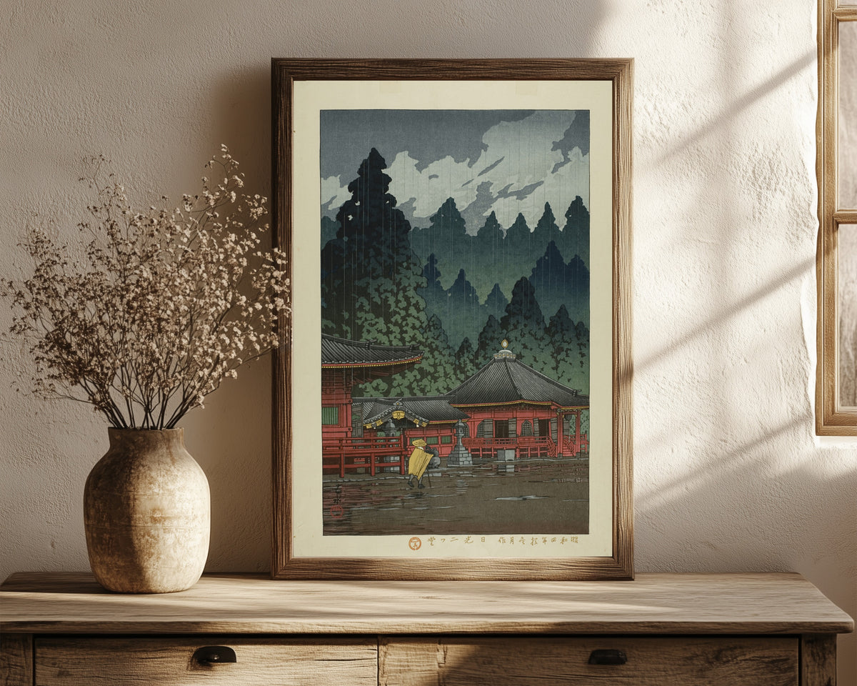Framed art print of Futatsudo Hall, Nikko by Kawase Hasui, in a dark wood frame leaning on a rustic console beside dried flowers