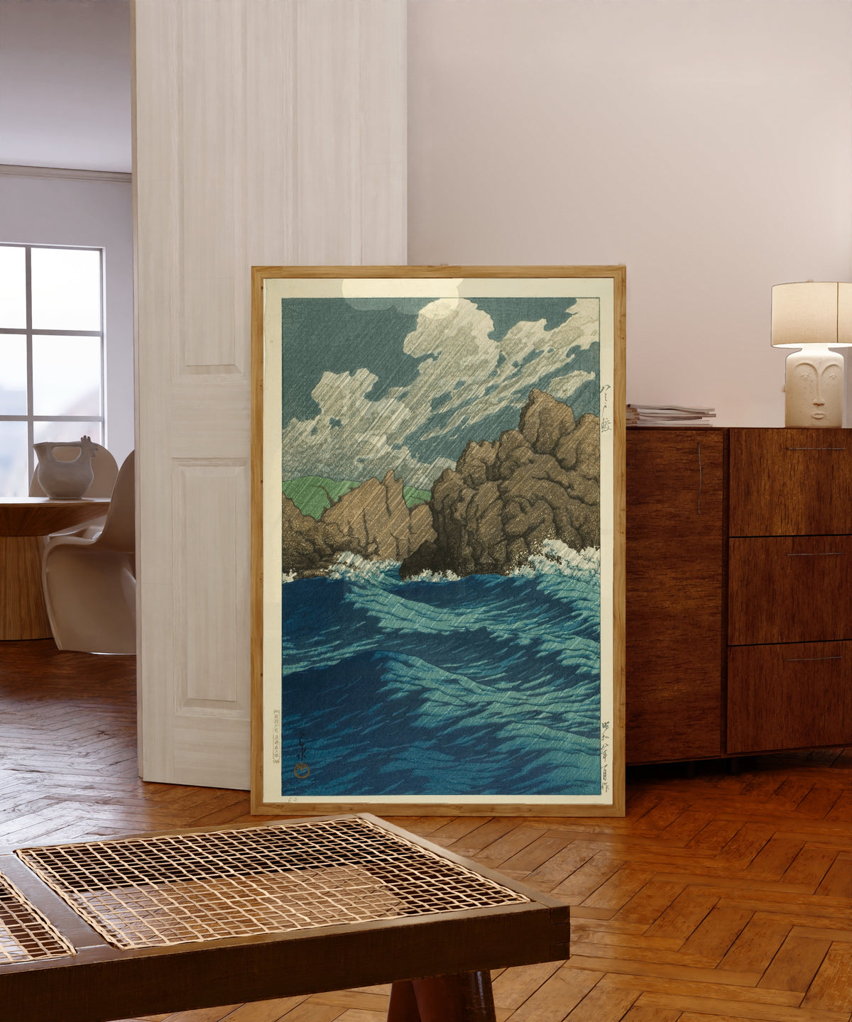 Framed art print of Hachinohe Same by Kawase Hasui, in a light wood frame leaning in a warm room with a parquet floor