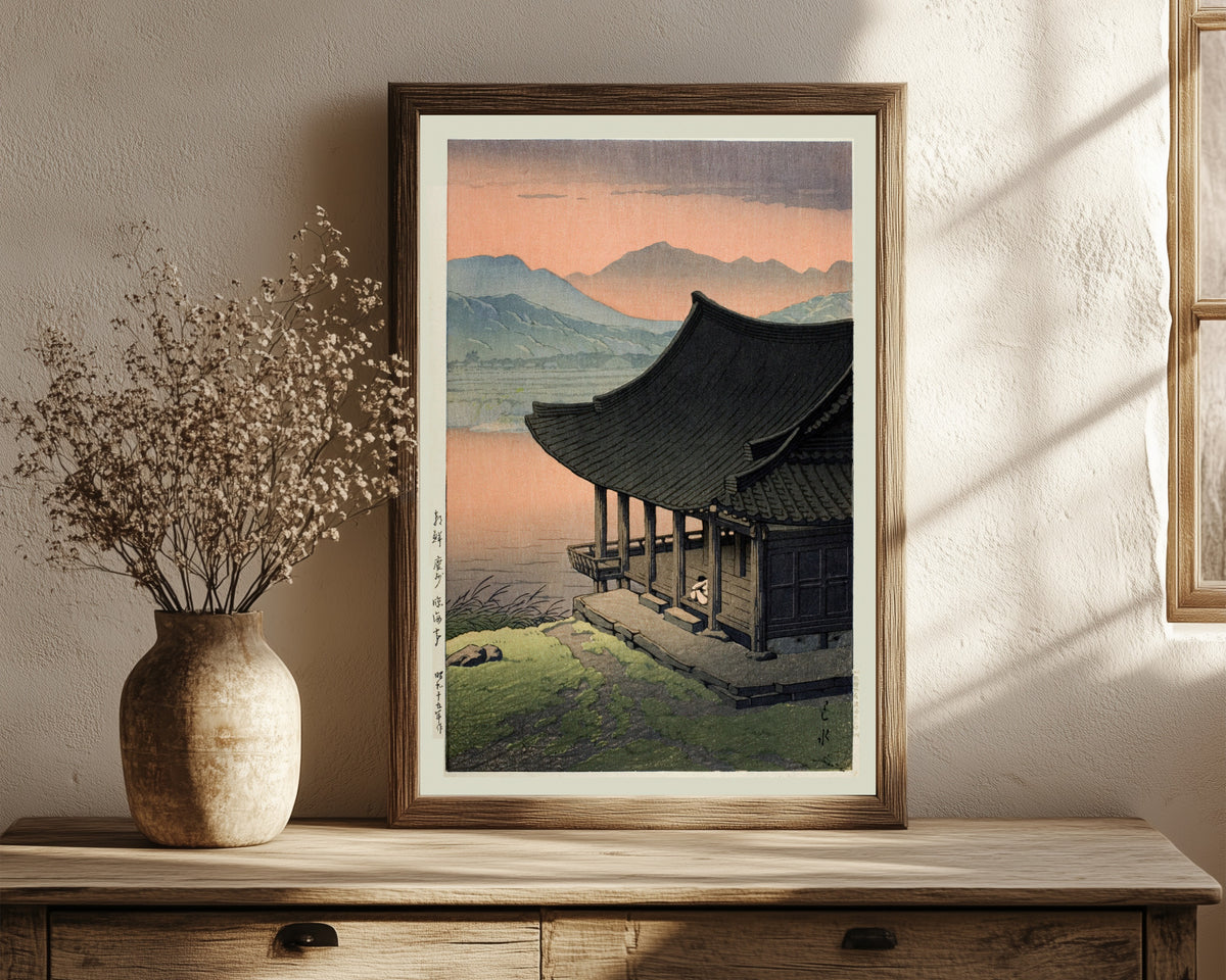 Framed art print of Imhae Pavillion by Kawase Hasui, in a dark wood frame leaning on a rustic console beside dried flowers