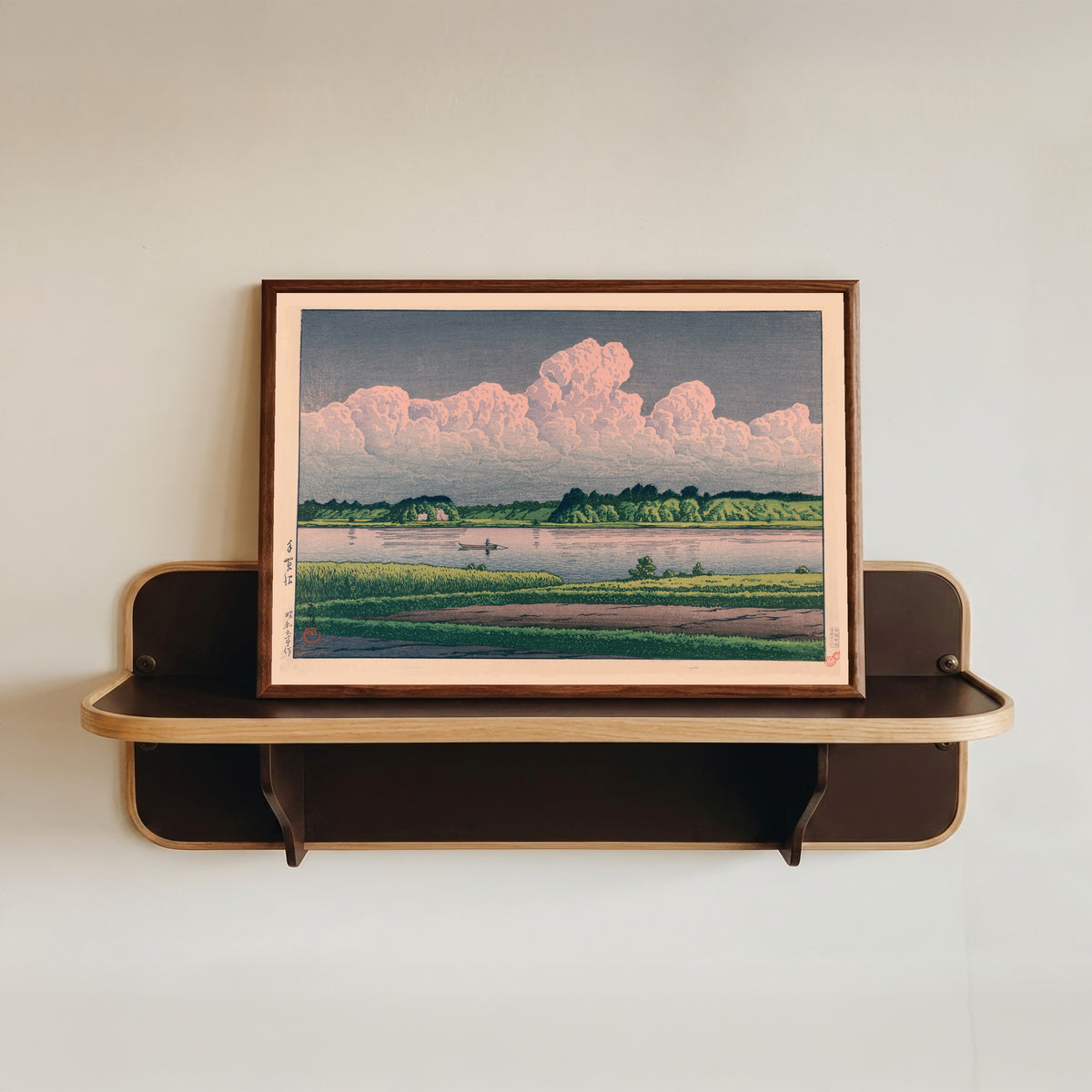 Framed art print of Lake Teganuma by Kawase Hasui, in a dark wood frame resting on a wall shelf