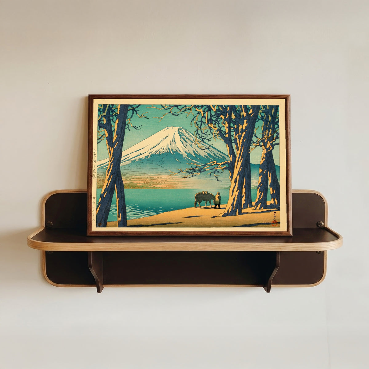 Framed art print of Late Autumn at Lake Yamanaka by Kawase Hasui, in a dark wood frame resting on a wall shelf