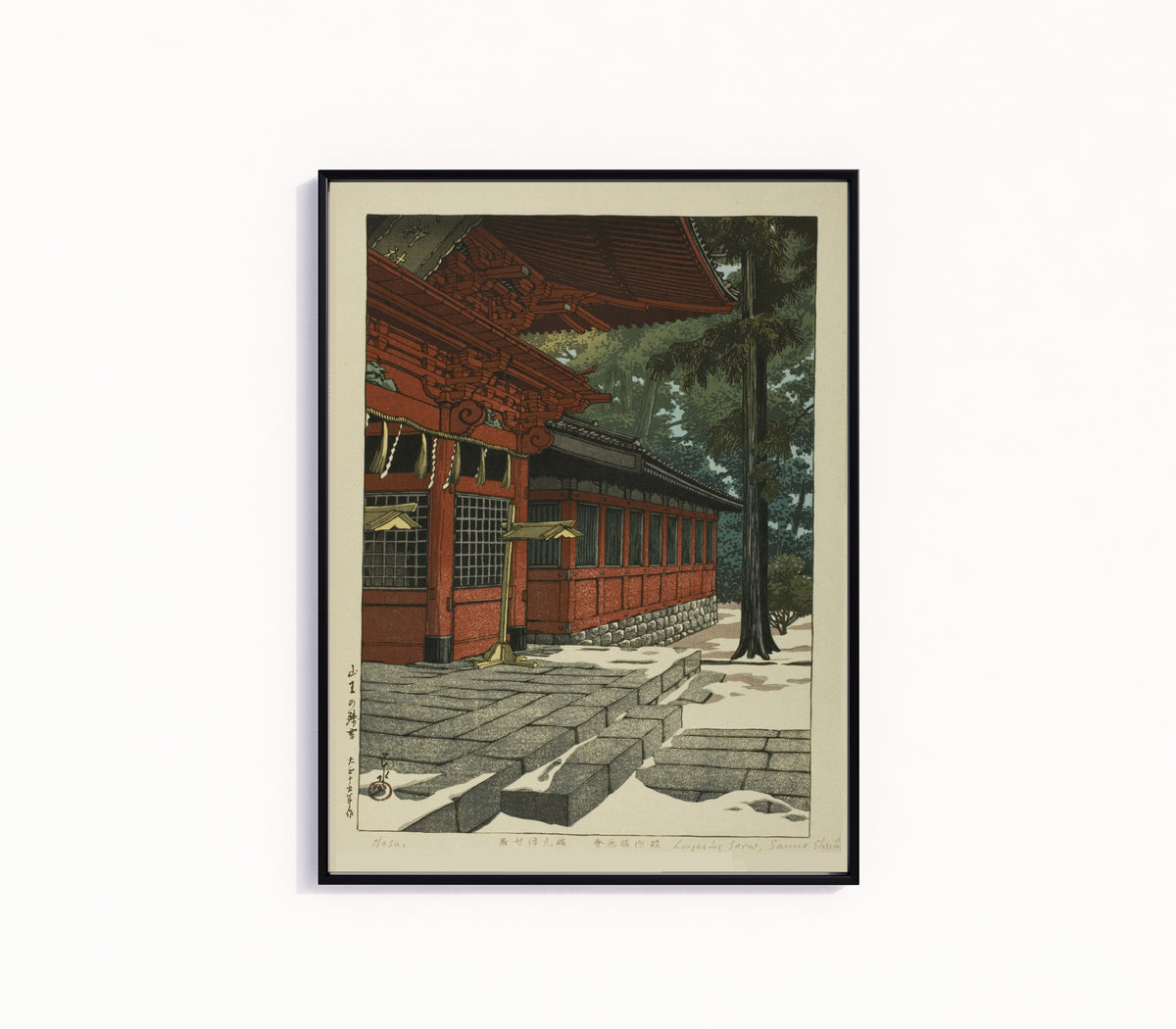 Framed art print of Lingering Snow at Sanno by Kawase Hasui, in a slim black frame on a plain white wall