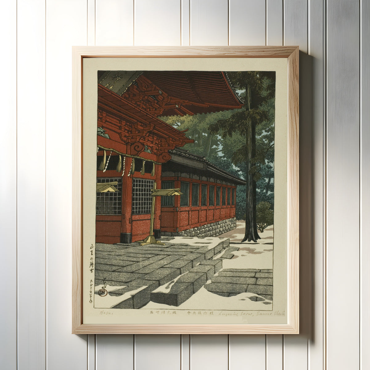 Framed art print of Lingering Snow at Sanno by Kawase Hasui, in a light wood frame on a white panelled wall
