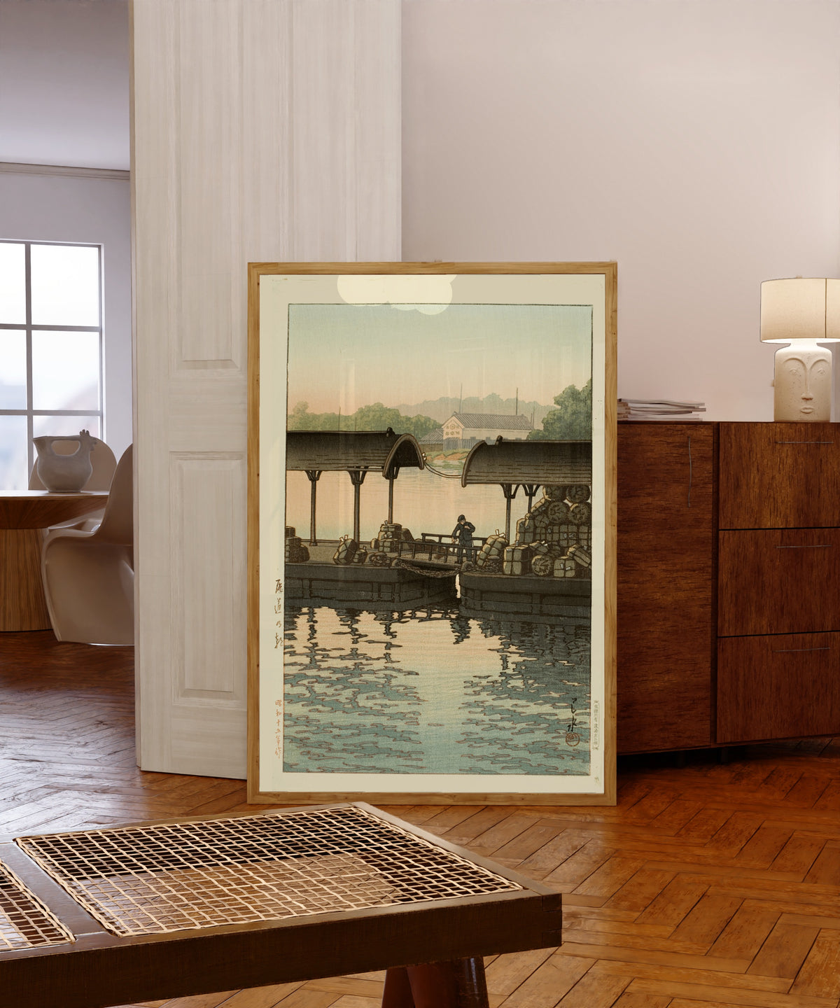 Framed art print of Morning at Onomichi by Kawase Hasui, in a light wood frame leaning in a warm room with a parquet floor