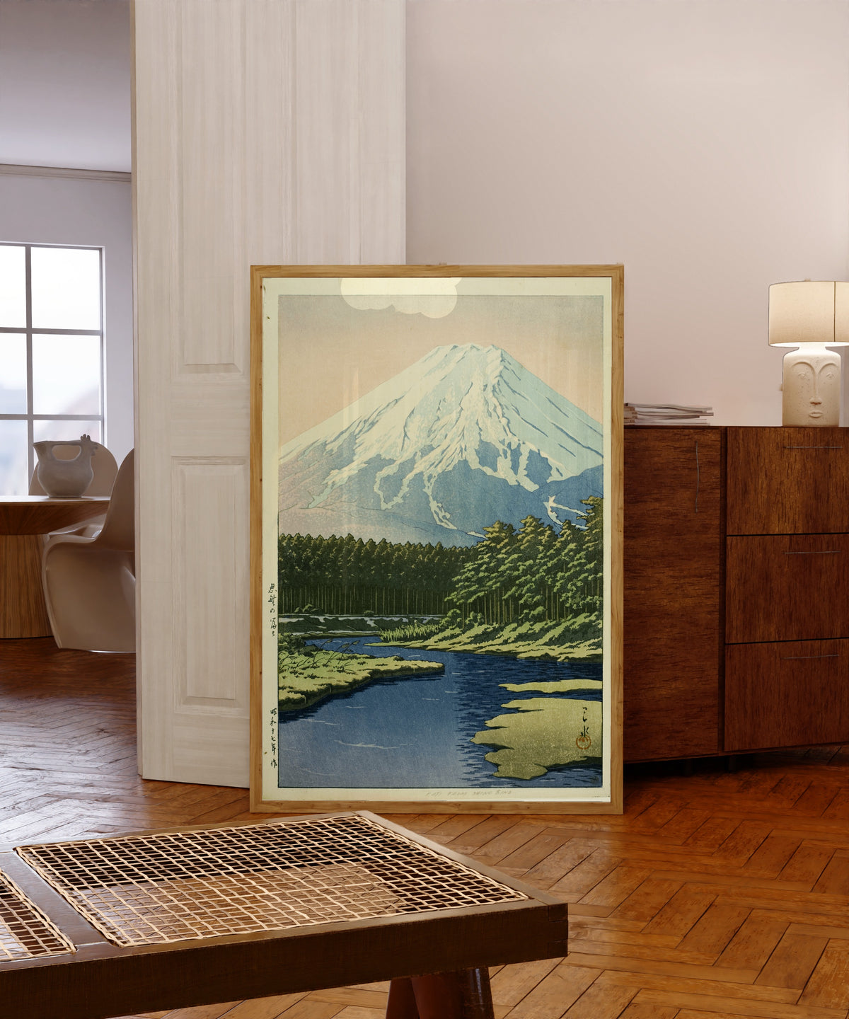 Framed art print of Mount Fuji from Oshino by Kawase Hasui, in a light wood frame leaning in a warm room with a parquet floor