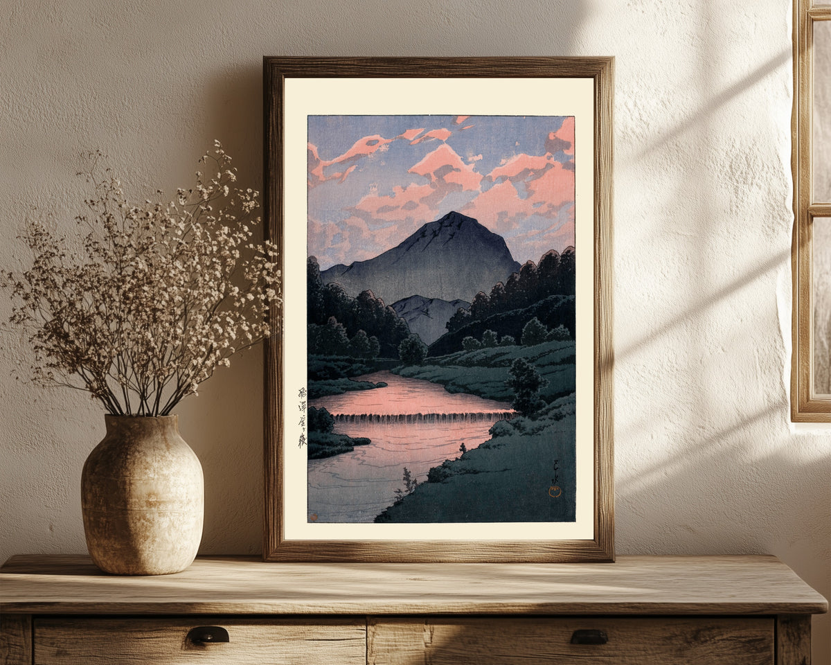 Framed art print of Mount Kamagatake, Hida by Kawase Hasui, in a dark wood frame leaning on a rustic console beside dried flowers