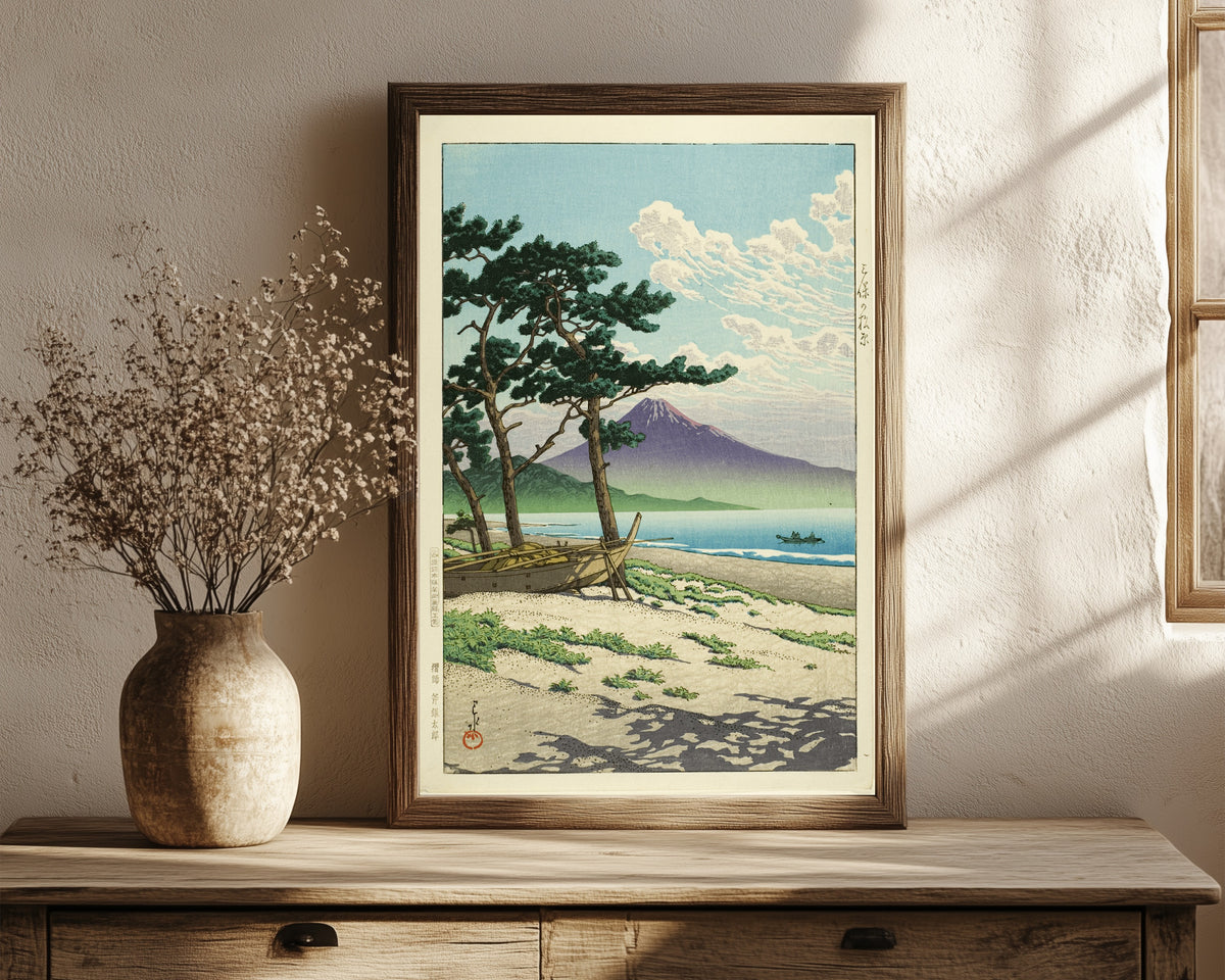 Framed art print of Pine Beach at Miho, Matsubara by Kawase Hasui, in a dark wood frame leaning on a rustic console beside dried flowers