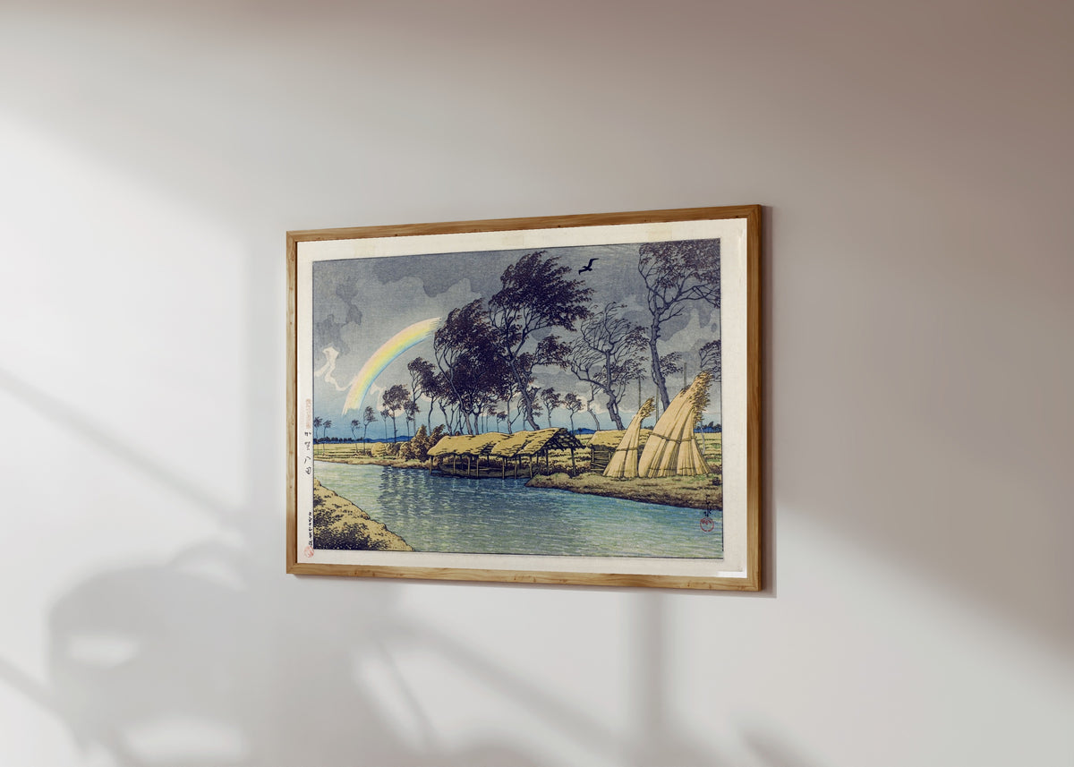 Framed art print of Rainbow at Hatta, Kaga Province by Kawase Hasui, in a light wood frame on a sunlit white wall, seen at a slight angle