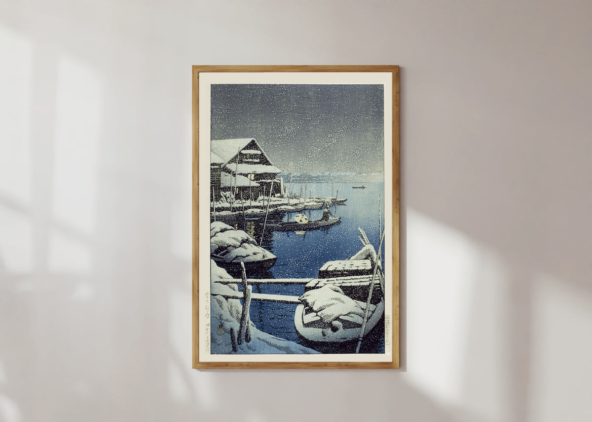 Framed art print of Snow at Mukojima by Kawase Hasui, in a light wood frame on a sunlit white wall