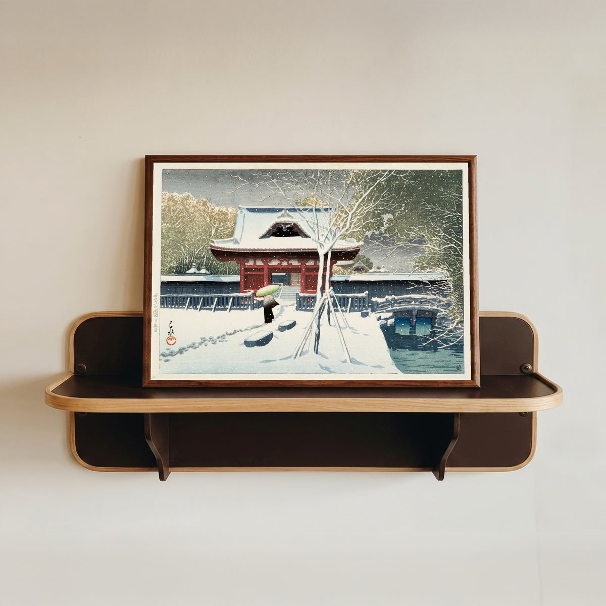 Framed art print of Snow at Shiba Park by Kawase Hasui, in a dark wood frame resting on a wall shelf