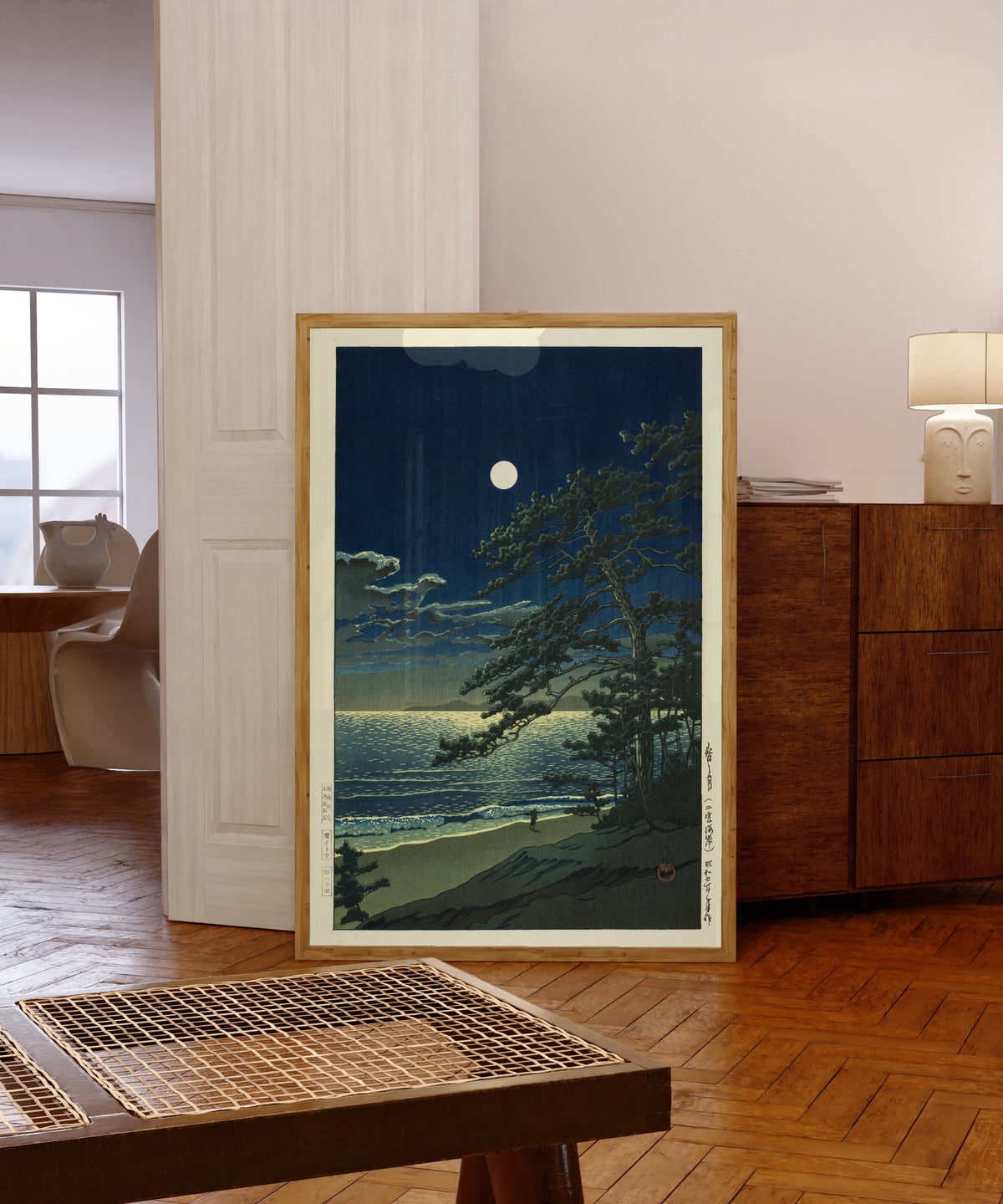 Framed art print of Spring Moon in Ninomiya Beach by Kawase Hasui, in a light wood frame leaning in a warm room with a parquet floor
