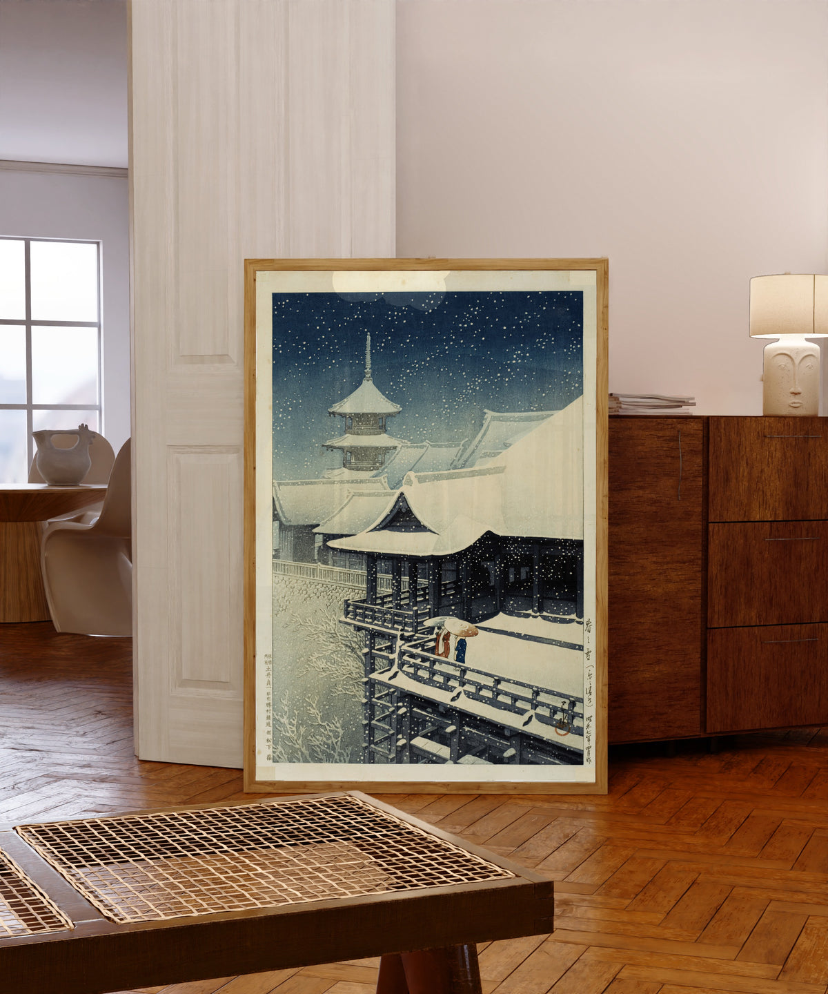 Framed art print of Spring Snow at Kiyomizu Temple, Kyoto by Kawase Hasui, in a light wood frame leaning in a warm room with a parquet floor