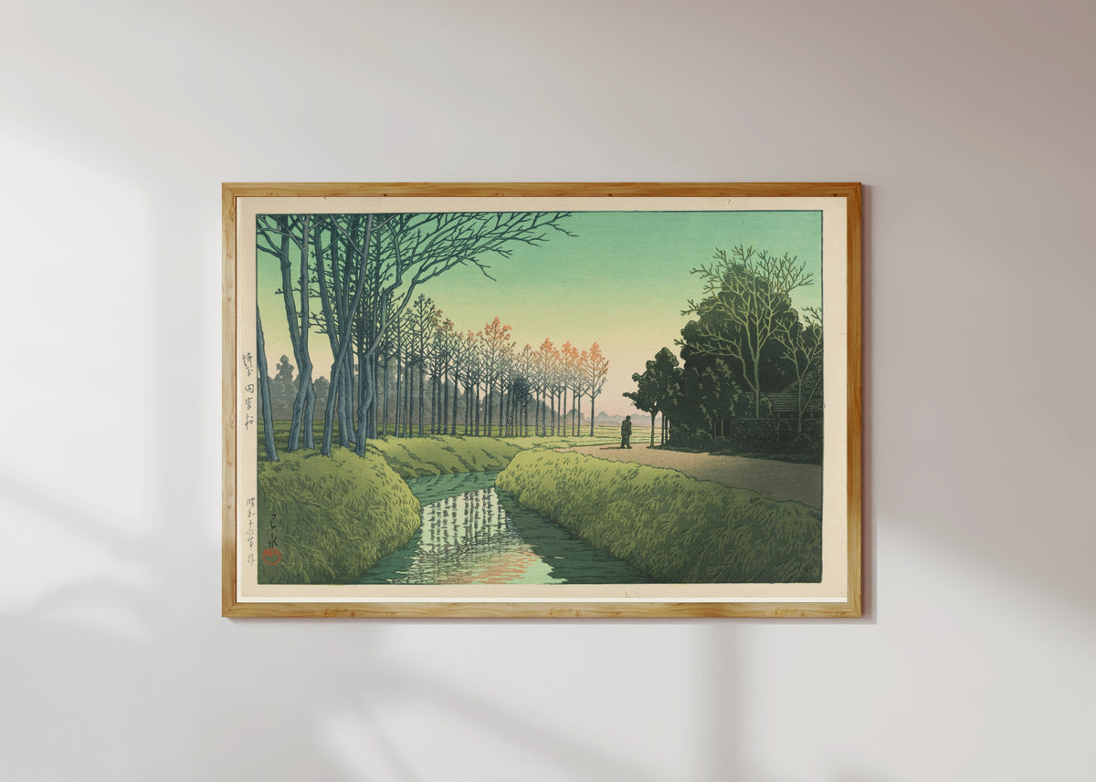 Framed art print of Tamiya Village by Kawase Hasui, in a light wood frame on a sunlit white wall
