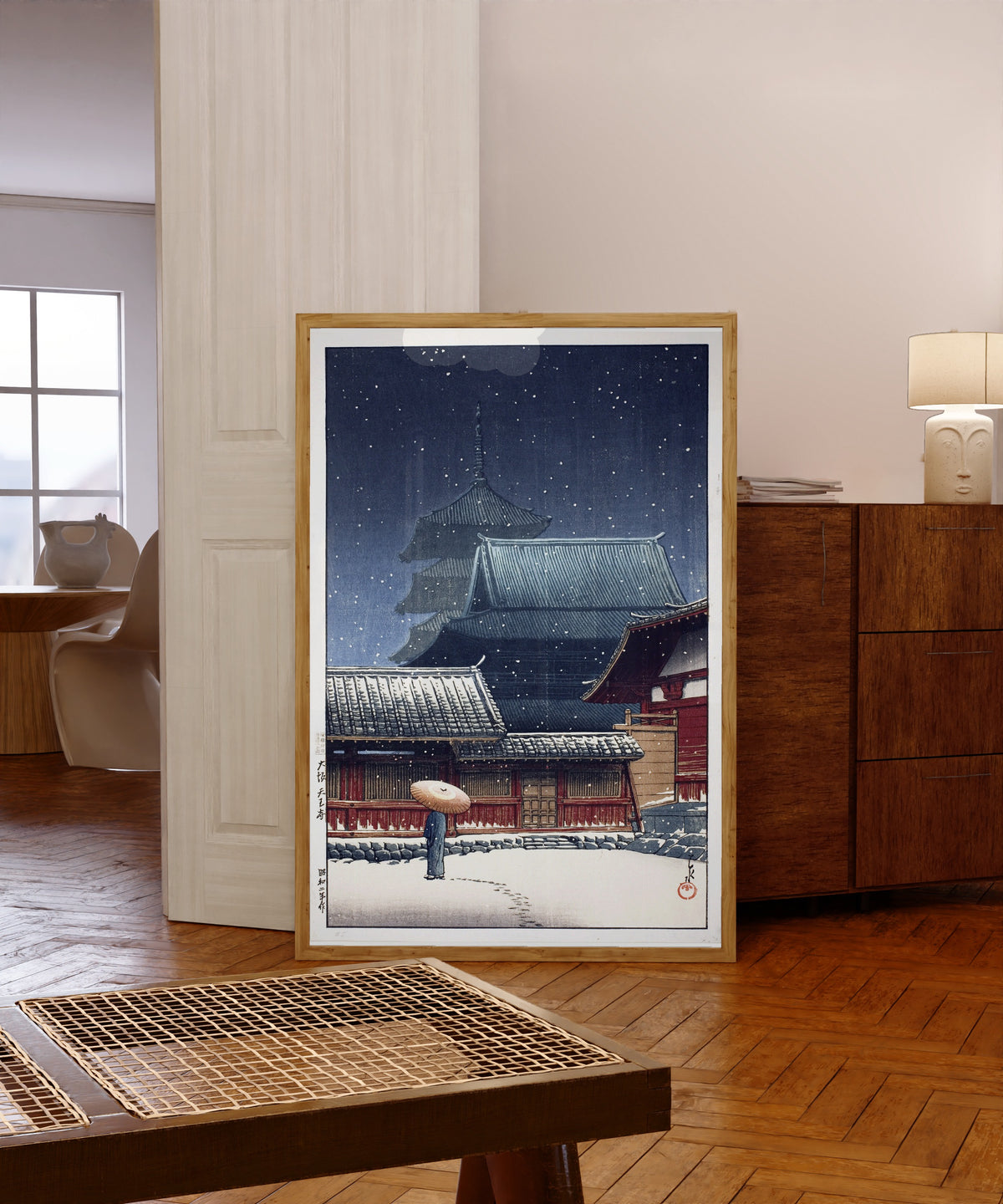 Framed art print of Tennoji Temple, Osaka, in Snow by Kawase Hasui, in a light wood frame leaning in a warm room with a parquet floor