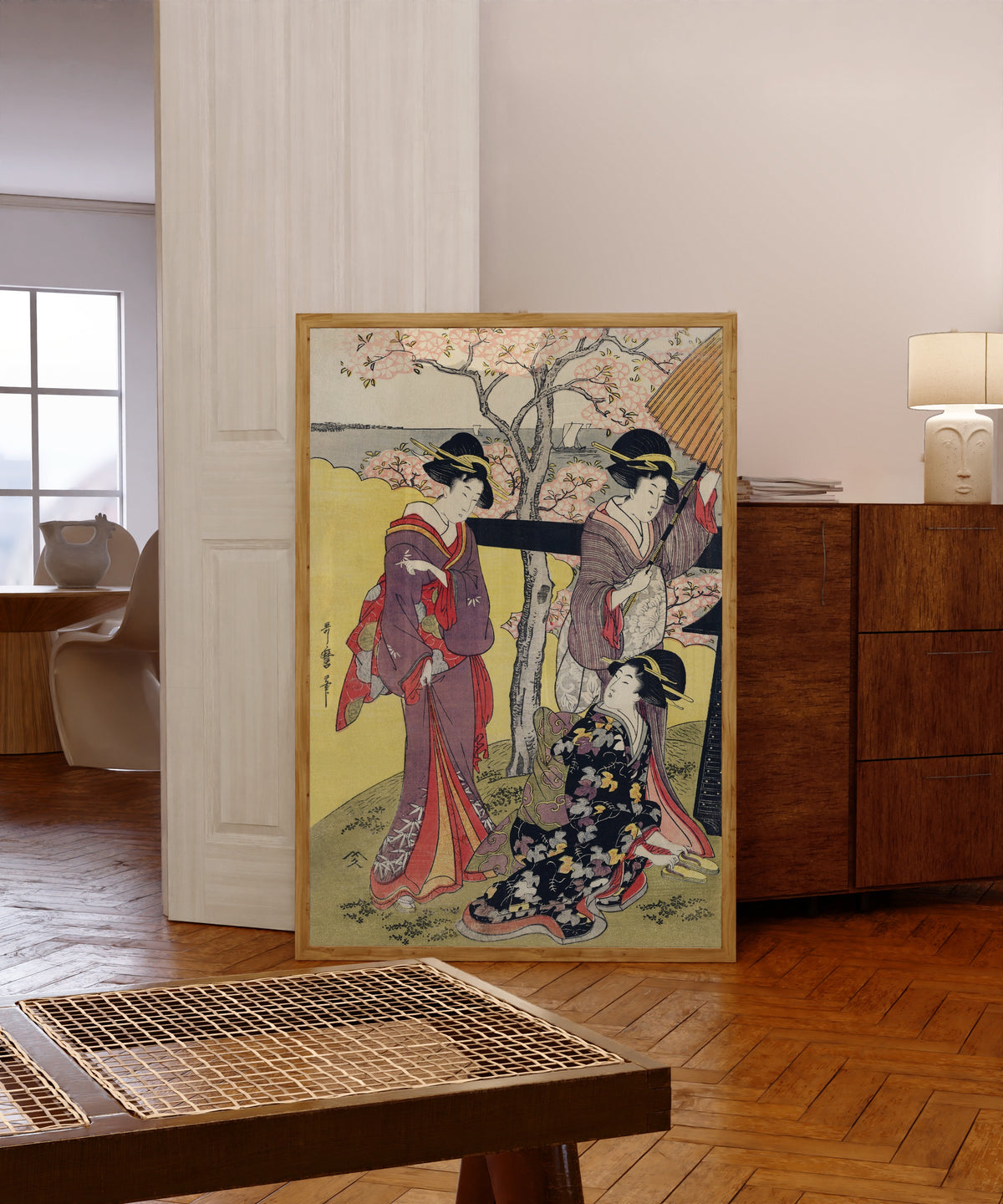 Framed art print of Gotenyama no Hanami Hidari by Kitagawa Utamaro, in a light wood frame leaning in a warm room with a parquet floor