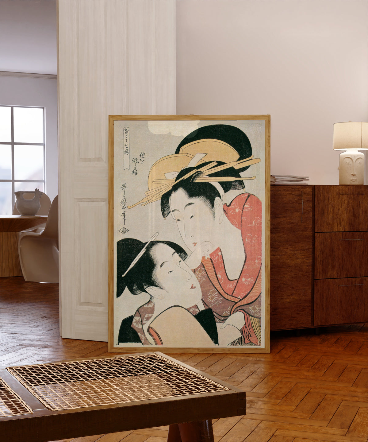 Framed art print of Habit of Slandering Others, from Seven Bad Habits by Kitagawa Utamaro, in a light wood frame leaning in a warm room with a parquet floor