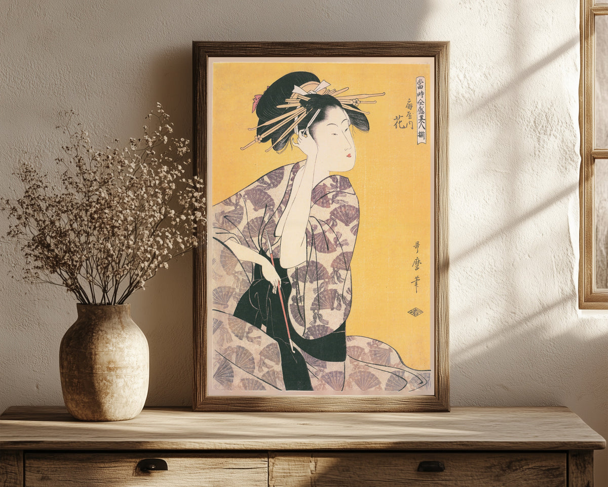 Framed art print of Hanaogi of the Ogiya (Holding a Pipe) by Kitagawa Utamaro, in a dark wood frame leaning on a rustic console beside dried flowers