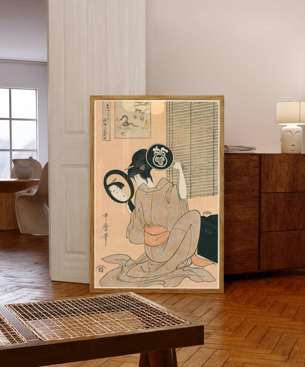 Framed art print of Ohisa of Takashimaya with Two Mirrors Set Against… by Kitagawa Utamaro, in a light wood frame leaning in a warm room with a parquet floor