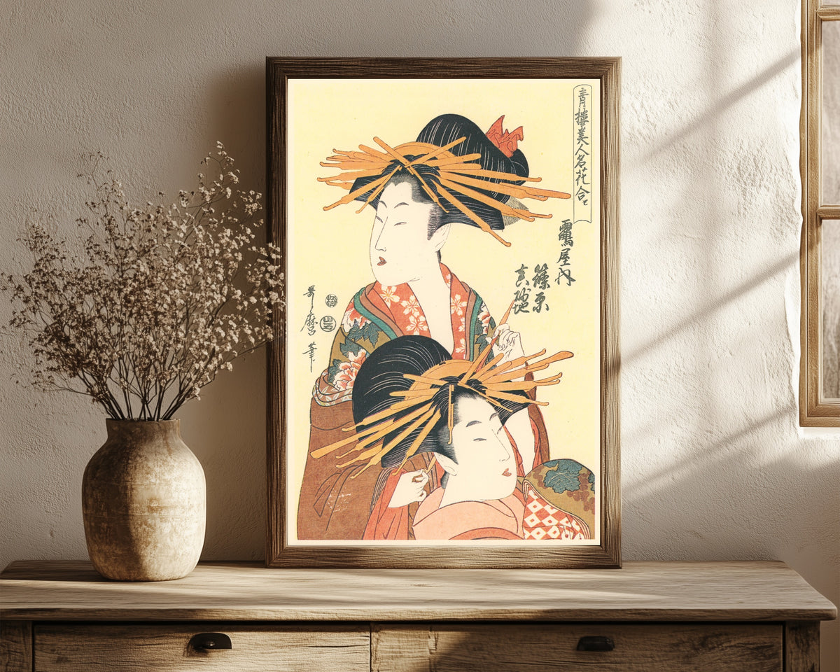 Framed art print of Shinohara and Masagi of the Tsuruya by Kitagawa Utamaro, in a dark wood frame leaning on a rustic console beside dried flowers