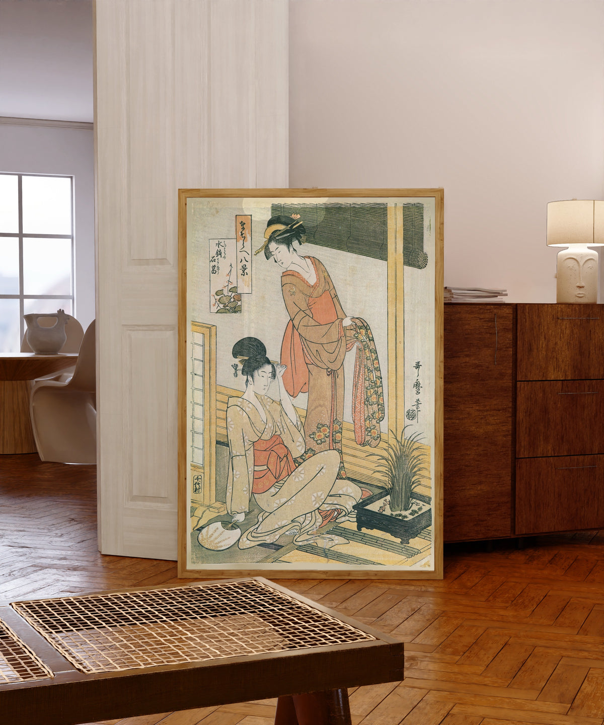 Framed art print of Sweet Flag in a Water Basin, from Eight Parody Views by Kitagawa Utamaro, in a light wood frame leaning in a warm room with a parquet floor