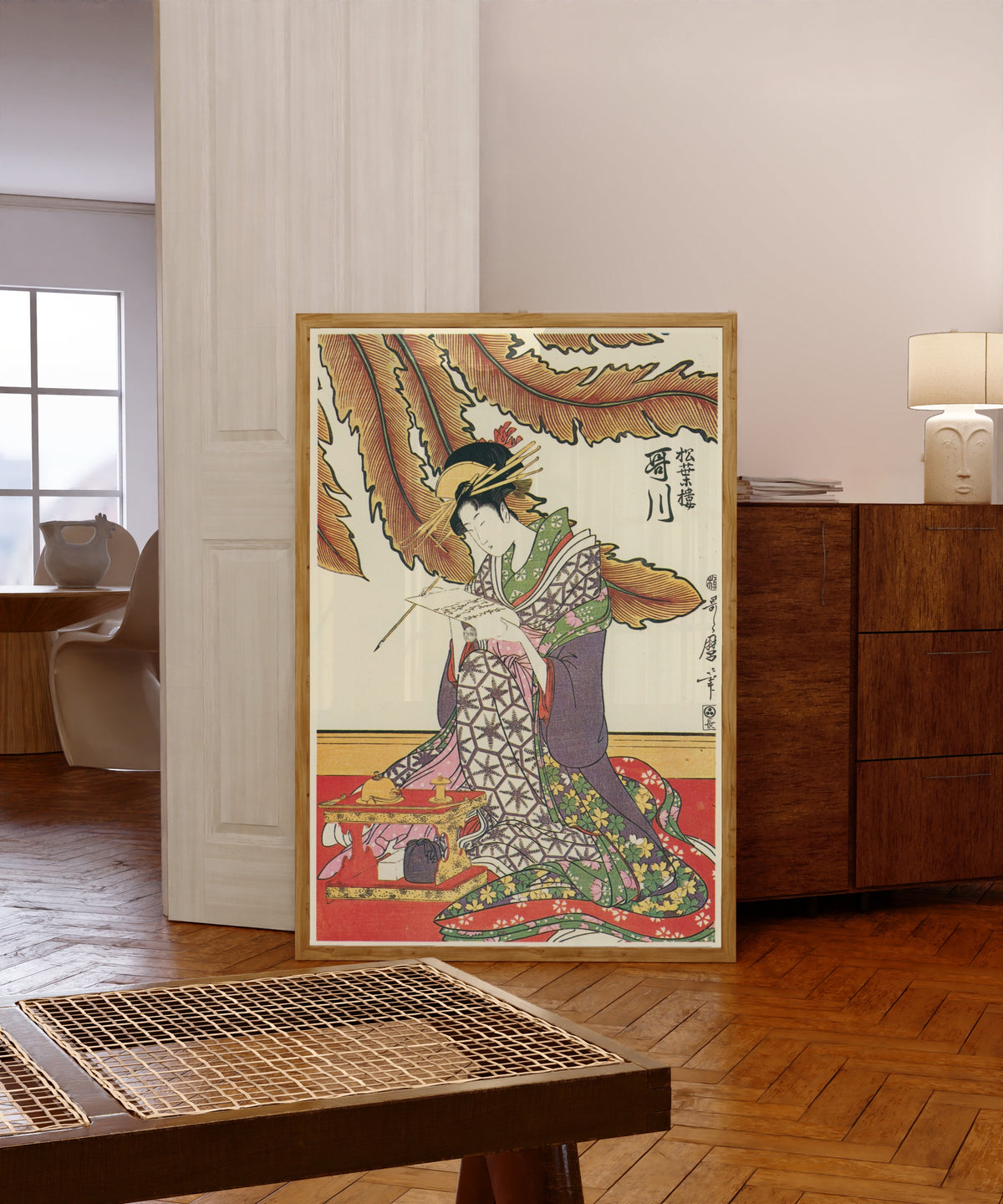 Framed art print of Three Beauties of Matsubaya: Utagawa by Kitagawa Utamaro, in a light wood frame leaning in a warm room with a parquet floor
