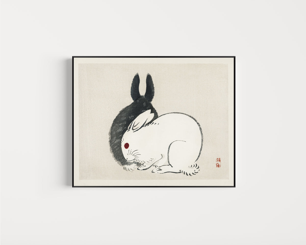 Framed art print of Black and White Rabbits by Kōno Bairei, in a slim black frame on a plain white wall